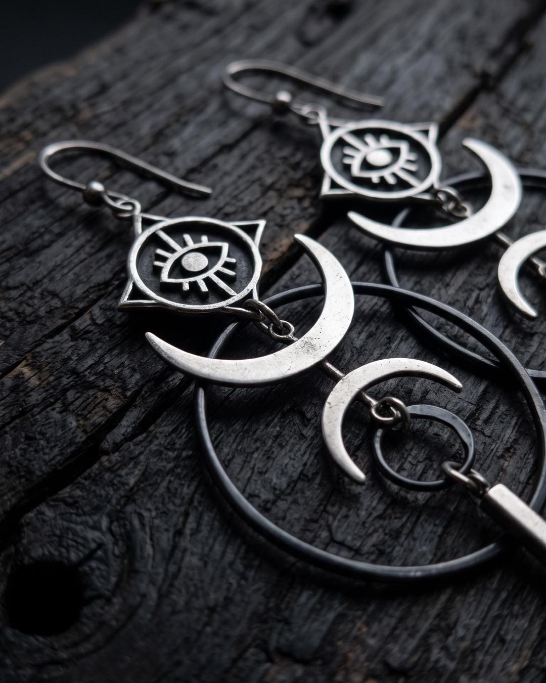 Silver crescent earrings worn against a dark background, showing movement in the long linear drop