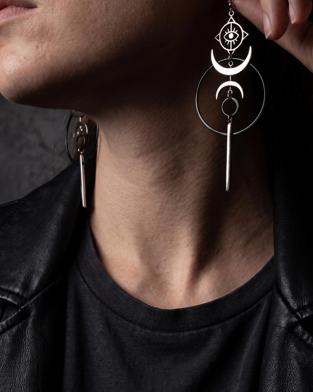 Flat lay of silver crescent earrings showing the full drop: eye panel, twin crescents, open circle, and tapered bar