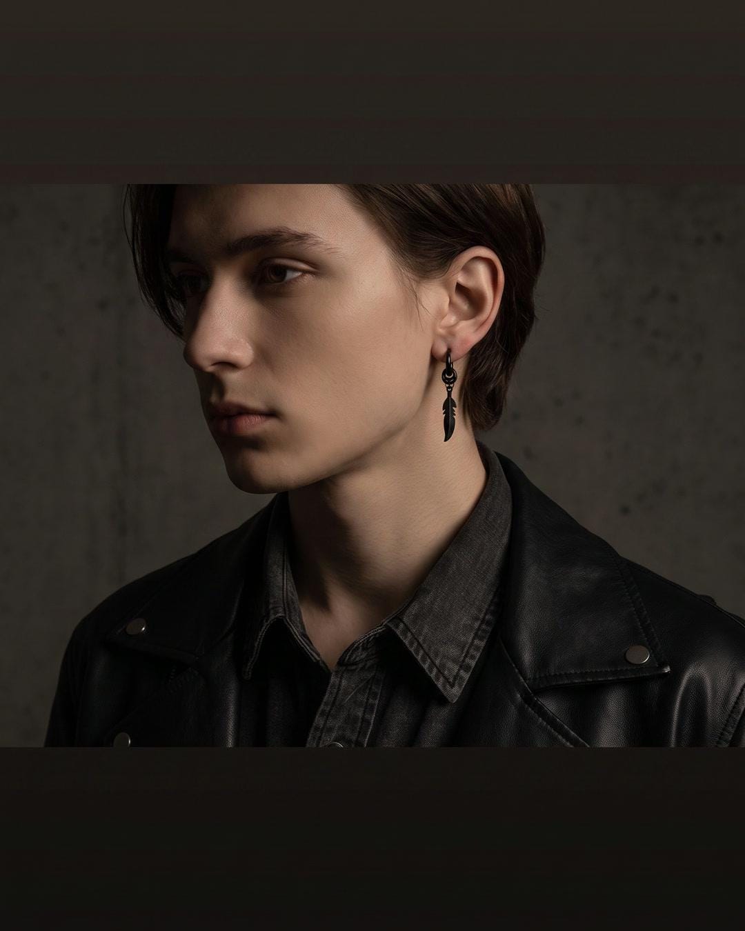 Feather charm huggie hoop earrings worn in a stacked ear with other small hoops