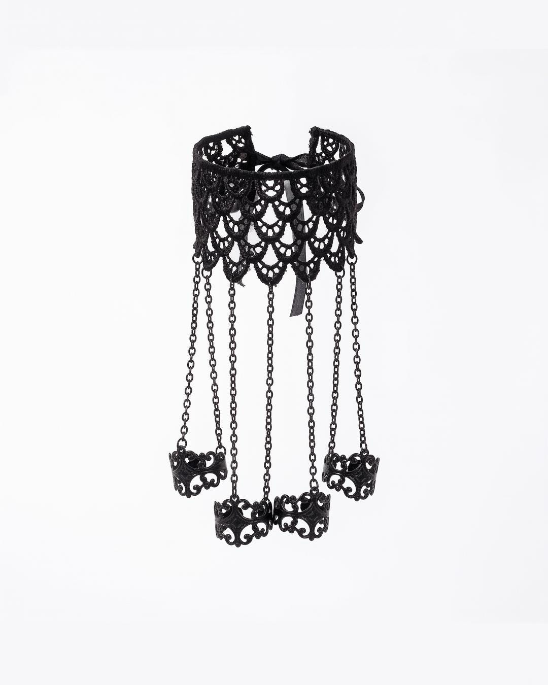 Flat lay of lace hand jewelry showing the black scalloped cuff, four chains, and pointed filigree rings.