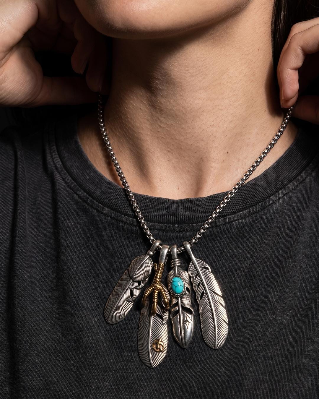 Four engraved feather pendants on a long box chain necklace with a talon, knot, and turquoise cabochon