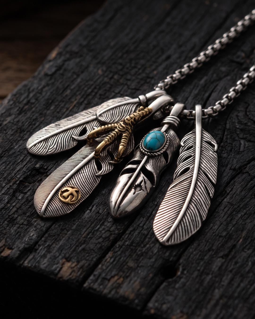 Long box chain necklace with feather cluster pendant worn over a black turtleneck