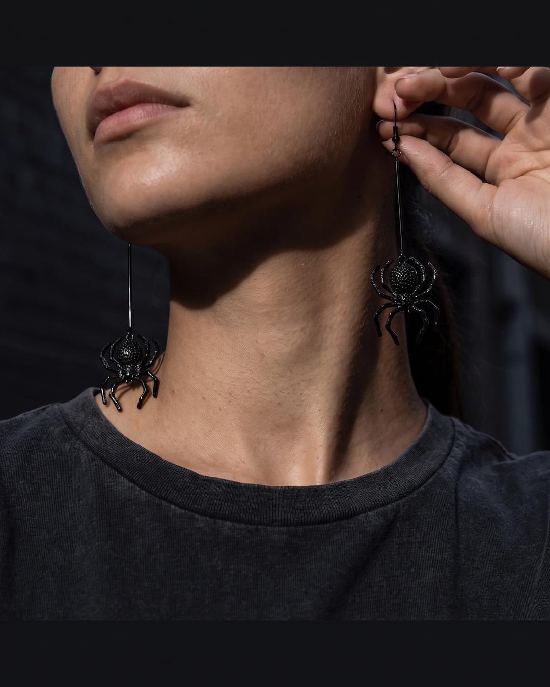 Matte black gothic spider drop earrings worn with hair up, spider drop swinging below the jaw