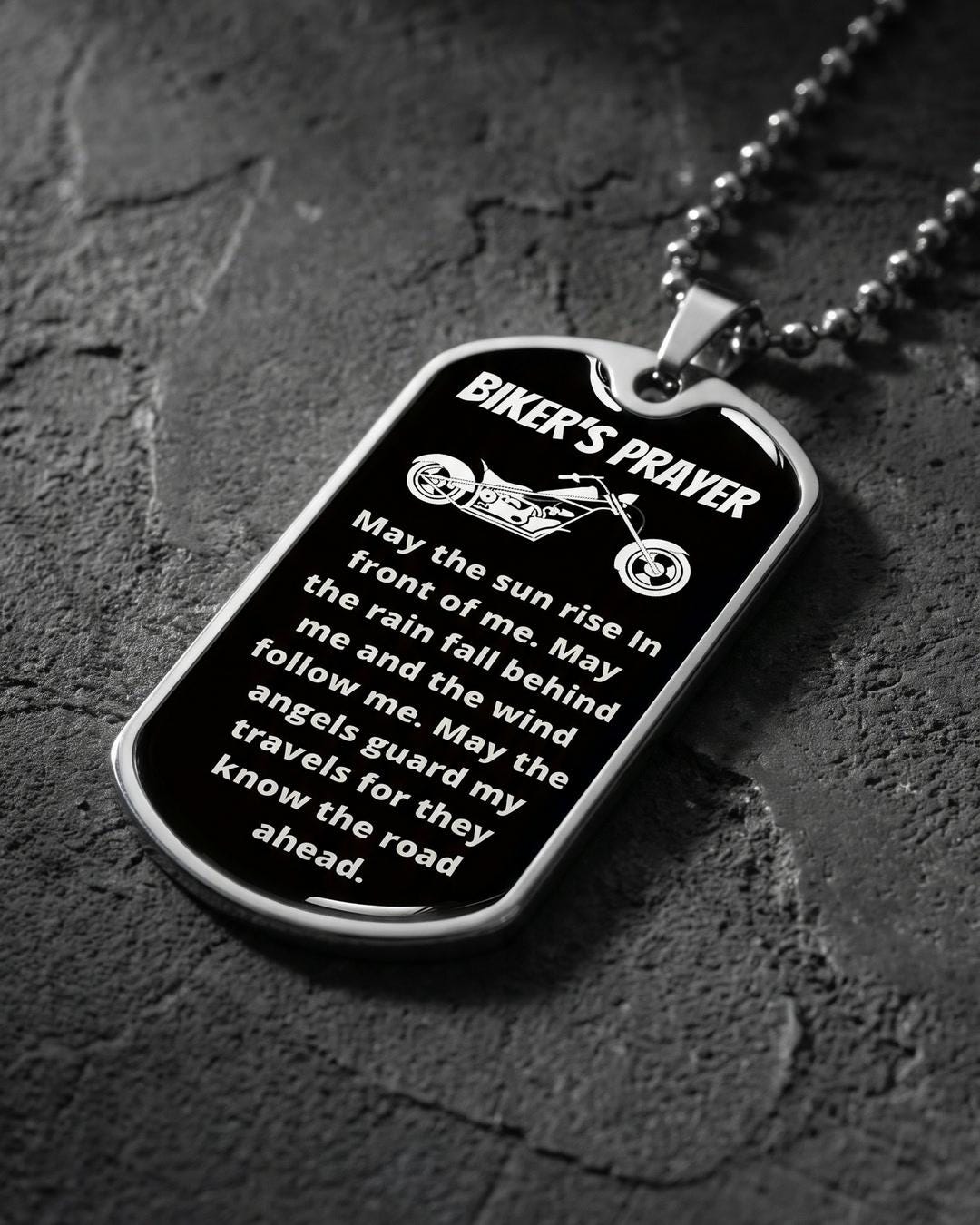 Close-up of a rider necklace showing the black face, white chopper engraving, and Biker's Prayer text
