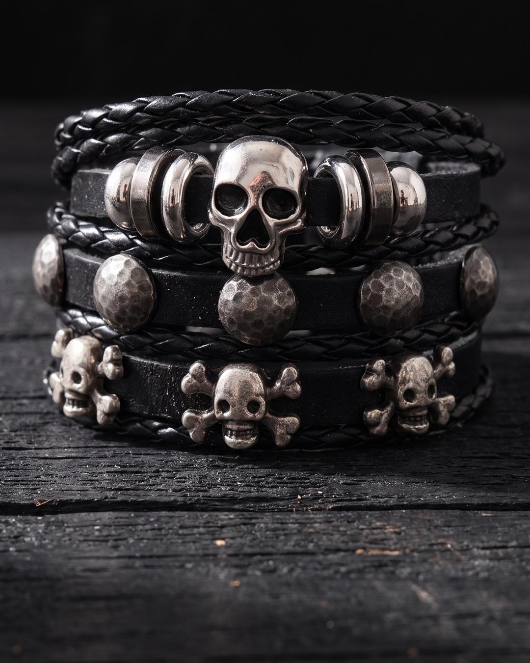Gothic skull stacking bracelet set worn on a wrist alongside silver rings and a chain bracelet