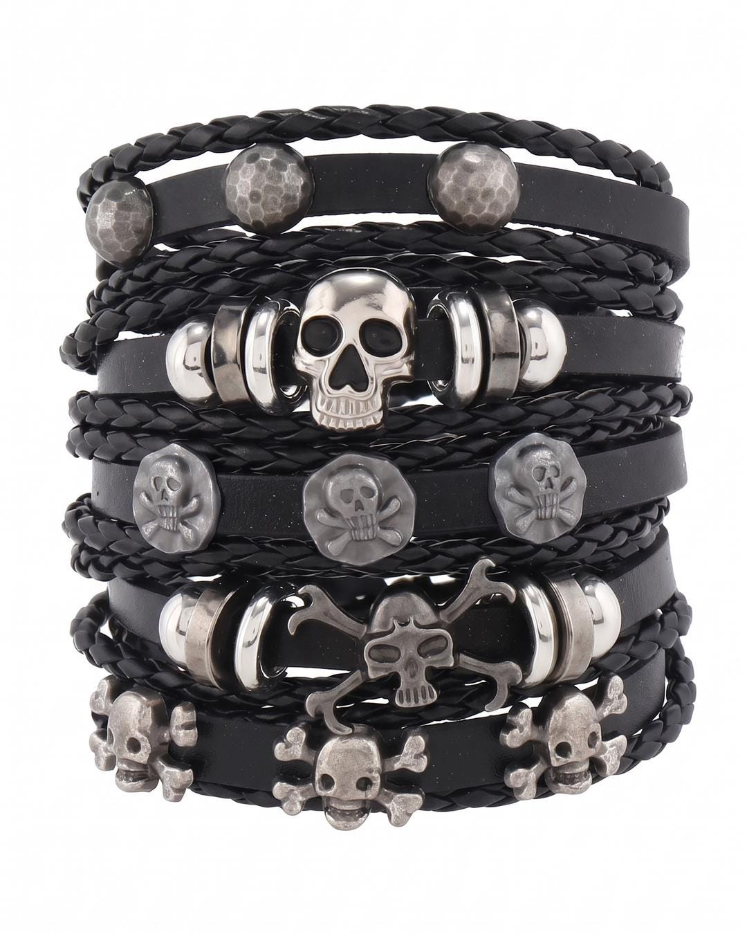Flat lay of a gothic skull stacking bracelet set showing five black bands with silver skull bead and crossbones studs