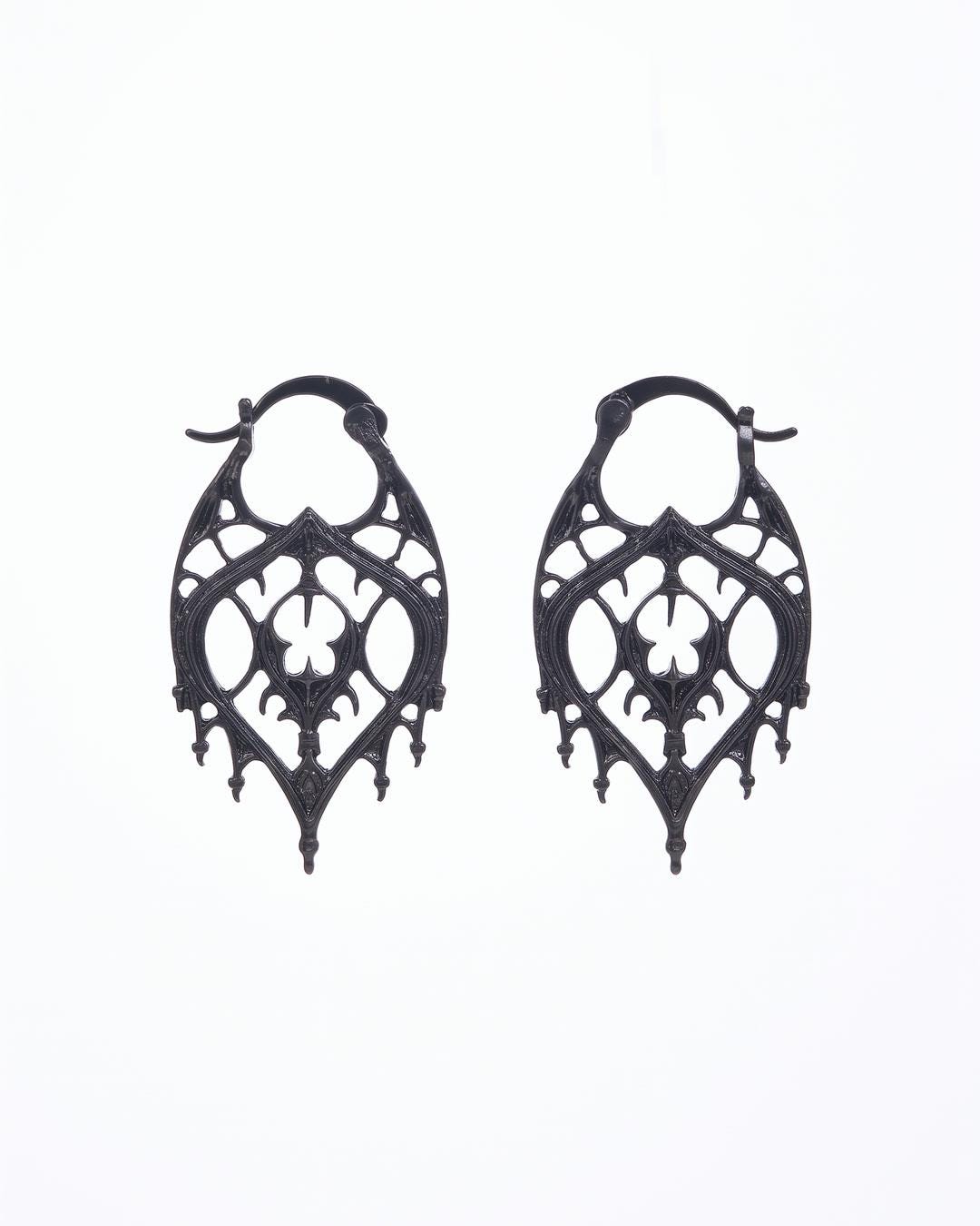 Close-up of black-tone teardrop earrings showing openwork arch tracery and dagger-point lower edge