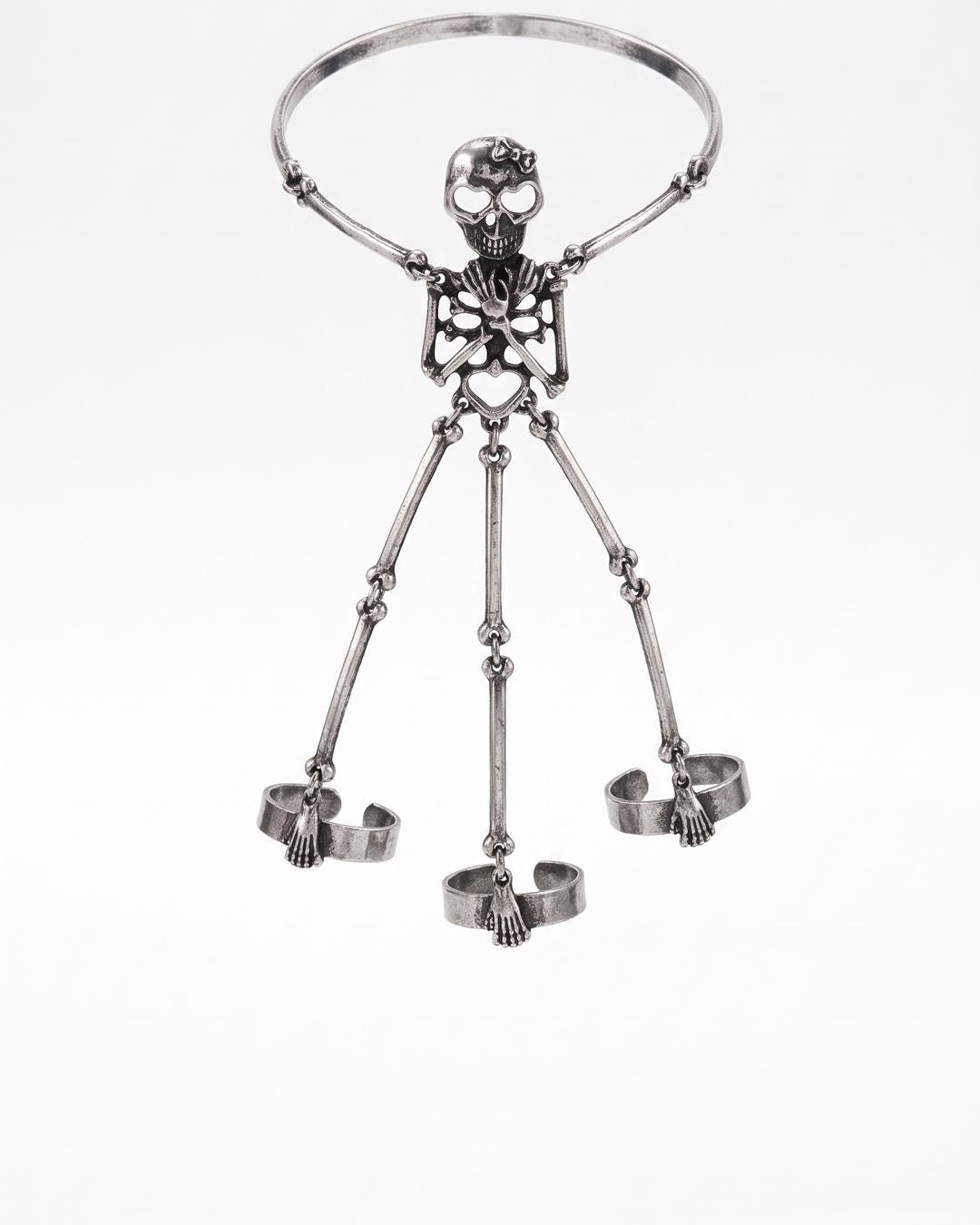 Flat lay of the antiqued silver skeleton hand chain showing full skeleton figure from skull to finger rings on a dark surface