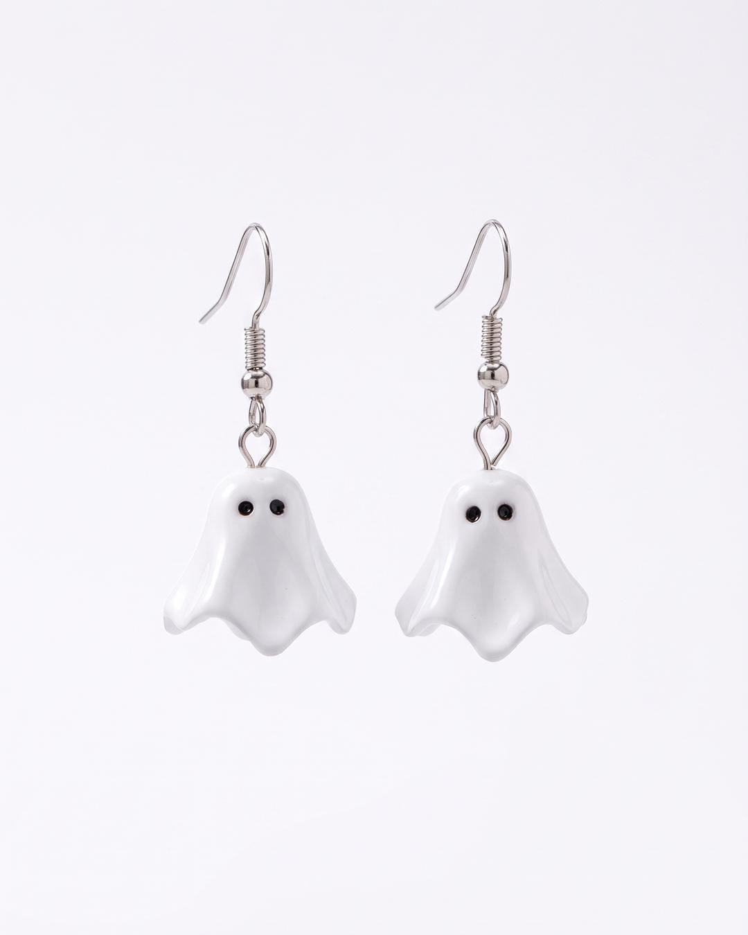 Glossy white ghost drop earrings with scalloped hems and black dot eyes on a silver-tone hook