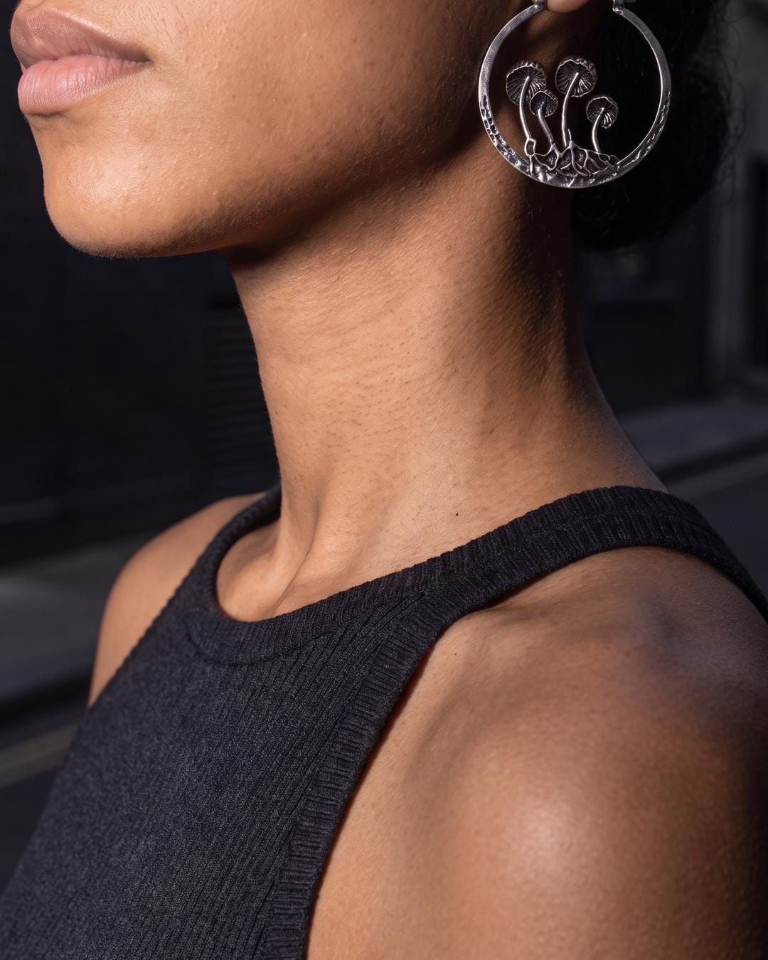 Antiqued silver mushroom hoop earrings worn against a dark velvet background with soft autumn lighting