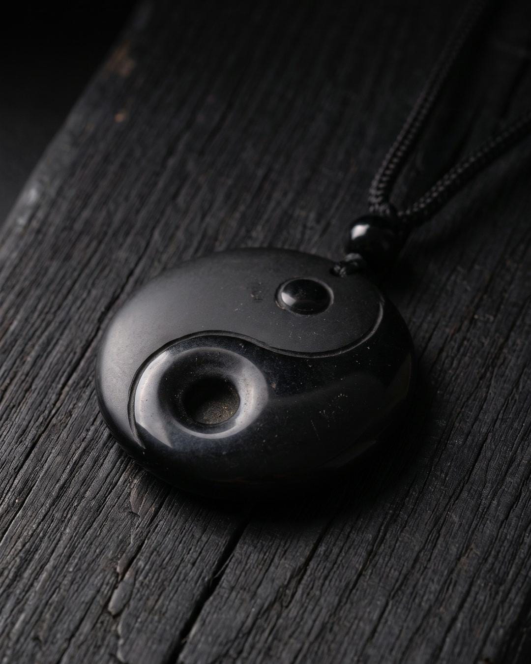 Close view of a black stone yin yang pendant necklace showing carved relief swirl and two recessed dot bosses